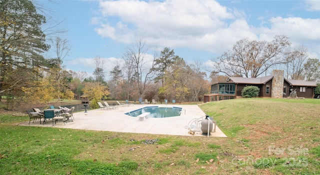 view of swimming pool with a diving board, a yard, a sunroom, and a patio area