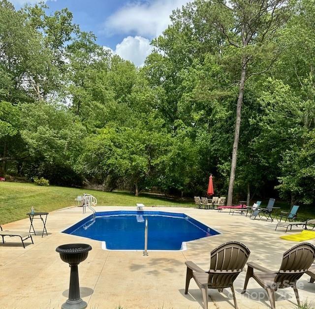 view of pool featuring a yard, a diving board, and a patio