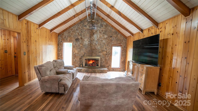 living room with dark hardwood / wood-style flooring, a fireplace, beam ceiling, and wood walls