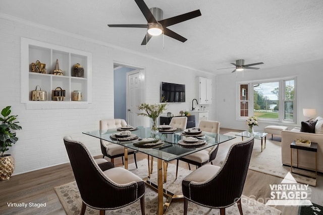 dining space with a textured ceiling, ornamental molding, ceiling fan, brick wall, and dark hardwood / wood-style flooring