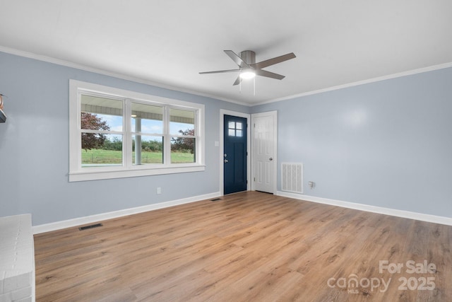 empty room with ceiling fan, light wood-type flooring, and crown molding