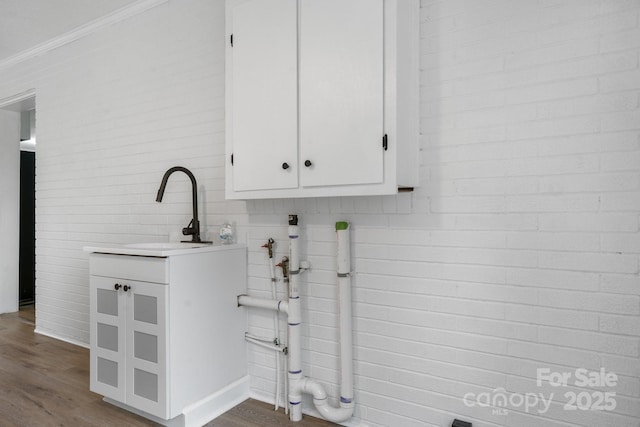 washroom featuring dark wood-type flooring, cabinets, ornamental molding, and sink