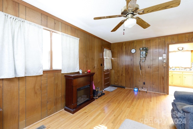 entrance foyer with wooden walls, ceiling fan, and light hardwood / wood-style floors