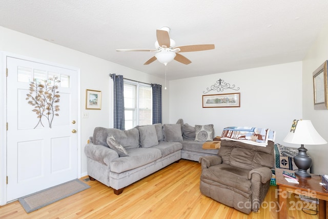 living room with hardwood / wood-style floors, ceiling fan, and a textured ceiling