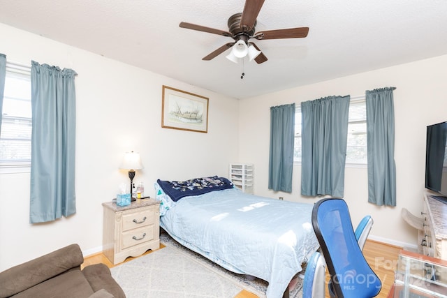 bedroom featuring a textured ceiling, light hardwood / wood-style flooring, multiple windows, and ceiling fan