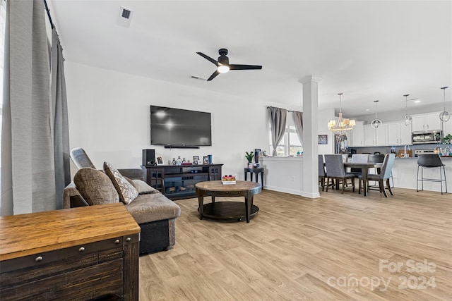 living room with ceiling fan with notable chandelier and light hardwood / wood-style flooring