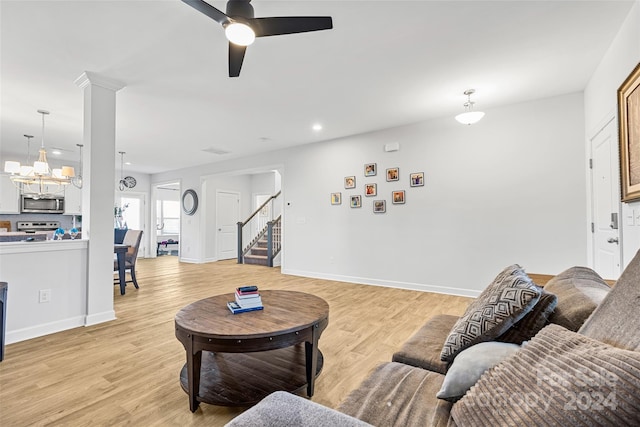 living room featuring ceiling fan with notable chandelier and light hardwood / wood-style floors