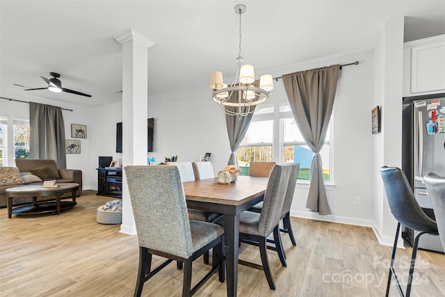 dining room with ceiling fan with notable chandelier, decorative columns, and light hardwood / wood-style flooring