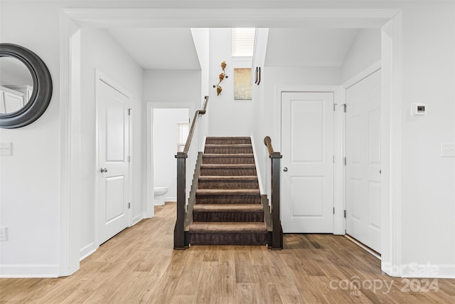 stairs with hardwood / wood-style flooring and vaulted ceiling