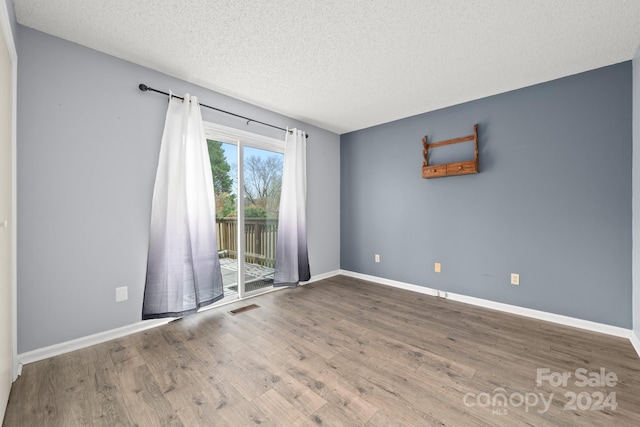 spare room featuring wood-type flooring and a textured ceiling