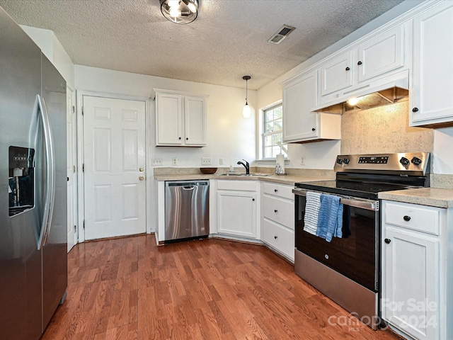 kitchen featuring stainless steel appliances, white cabinetry, hanging light fixtures, and sink