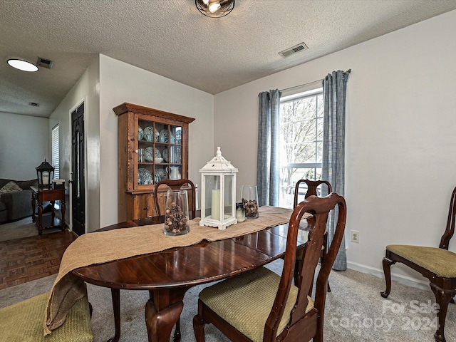 carpeted dining space featuring a textured ceiling