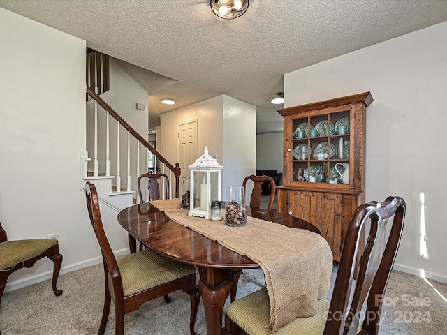 carpeted dining space featuring a textured ceiling