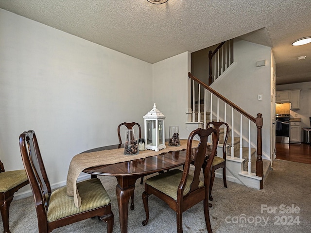 dining area with a textured ceiling and dark colored carpet