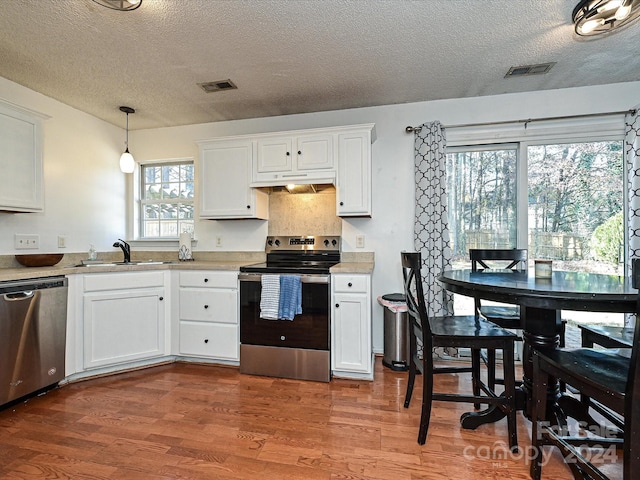 kitchen featuring white cabinetry, hanging light fixtures, hardwood / wood-style floors, a textured ceiling, and appliances with stainless steel finishes