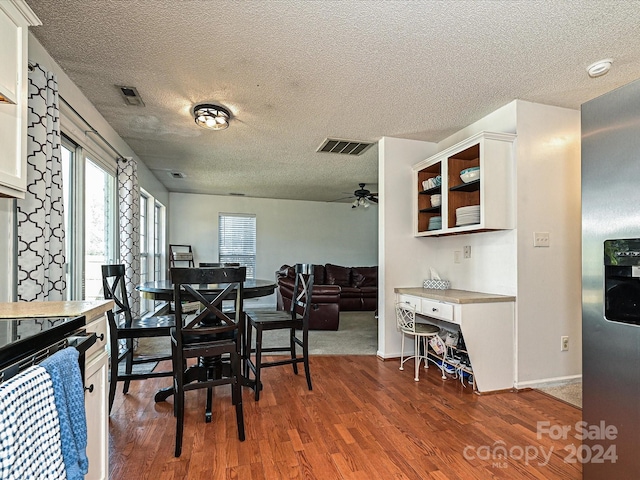 dining room with a textured ceiling, ceiling fan, and dark wood-type flooring