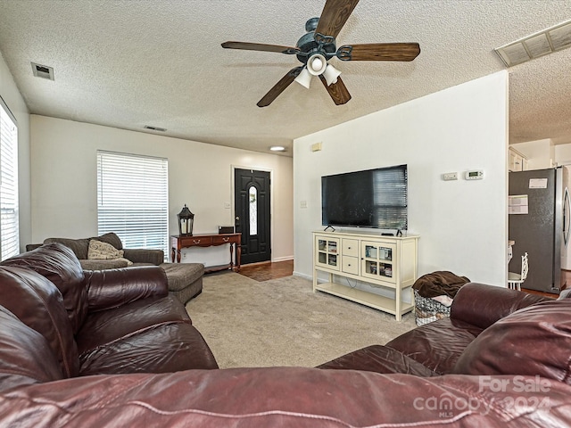 carpeted living room with ceiling fan and a textured ceiling