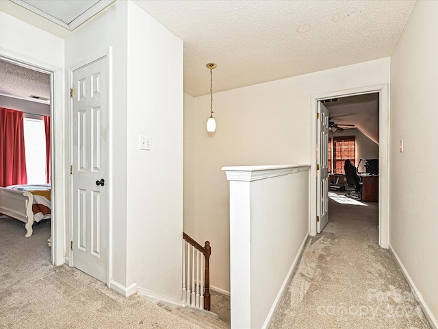 hallway with carpet, a textured ceiling, and vaulted ceiling