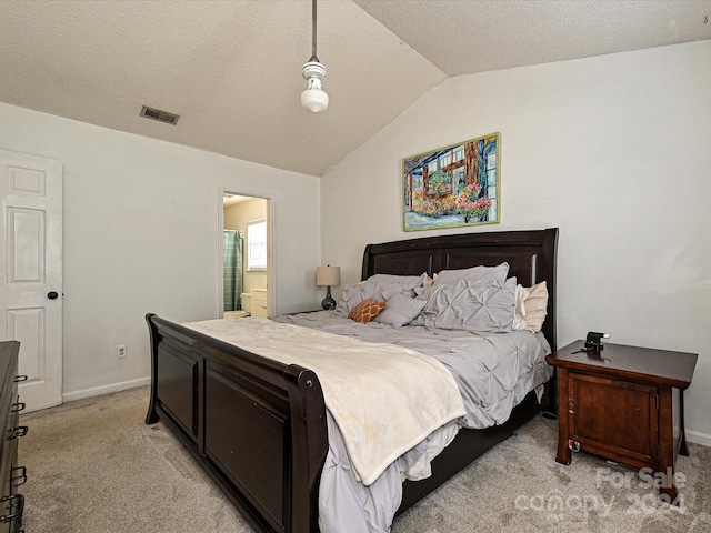 bedroom with a textured ceiling, ensuite bath, light carpet, and vaulted ceiling