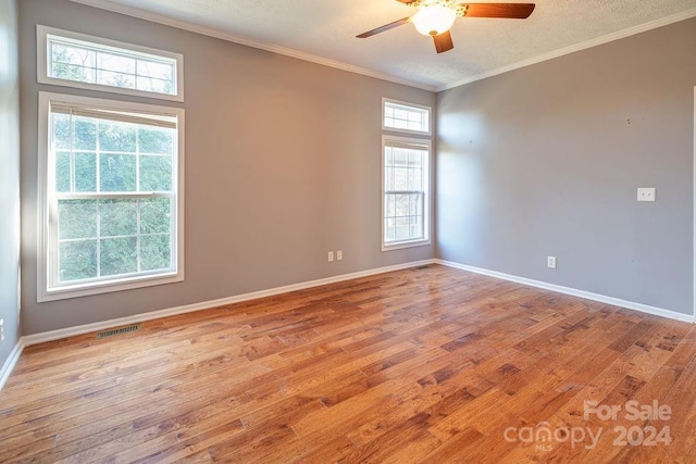 empty room with ceiling fan, light hardwood / wood-style floors, crown molding, and a wealth of natural light