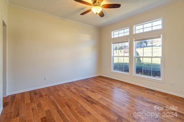 empty room with hardwood / wood-style floors, crown molding, and a textured ceiling