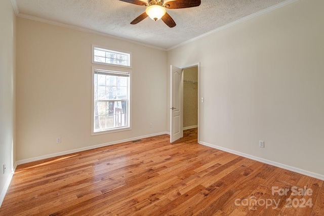 unfurnished room with a textured ceiling, light wood-type flooring, and ornamental molding