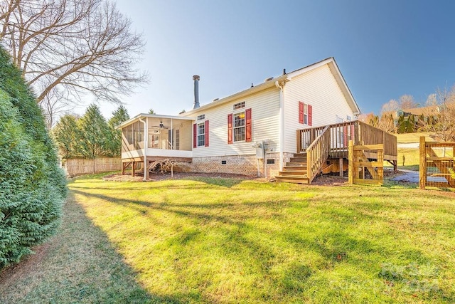 rear view of house with a lawn, a wooden deck, and a sunroom