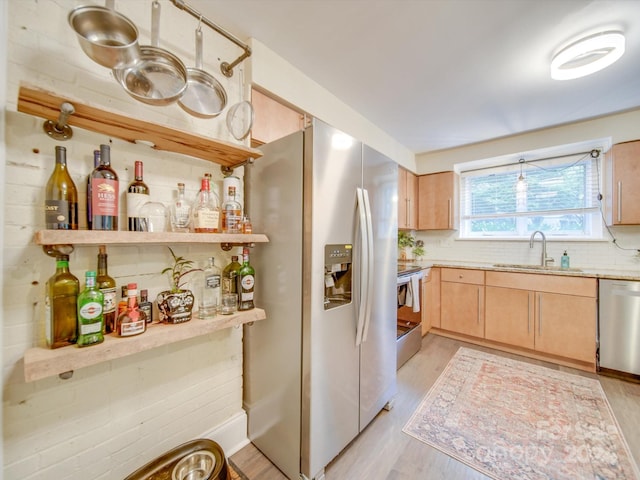 kitchen with sink, stainless steel appliances, backsplash, light brown cabinetry, and light wood-type flooring