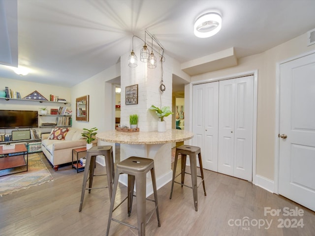 kitchen with hardwood / wood-style floors, a kitchen breakfast bar, and pendant lighting