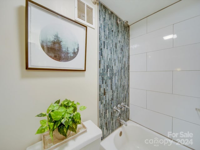 bathroom with tiled shower / bath combo and toilet