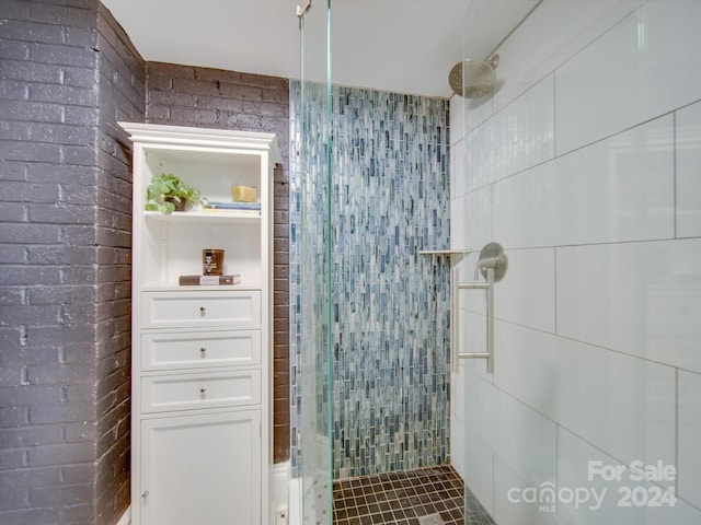 bathroom with tiled shower and brick wall