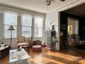 sitting room featuring hardwood / wood-style floors, ceiling fan, and ornamental molding