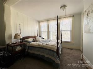 bedroom with dark colored carpet and multiple windows