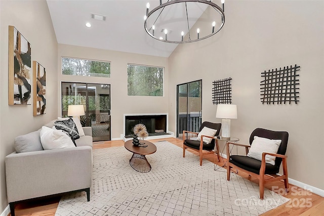 living room with an inviting chandelier, wood-type flooring, and high vaulted ceiling