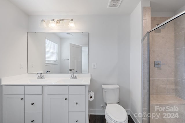 bathroom featuring a shower with door, vanity, and toilet