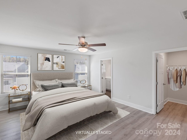 bedroom with a spacious closet, light wood-type flooring, multiple windows, and a closet