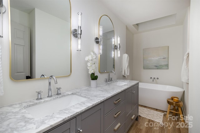 bathroom with hardwood / wood-style flooring, vanity, and a bathing tub