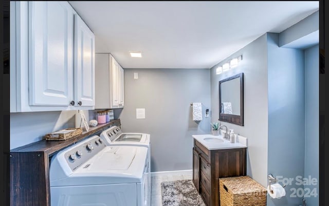 laundry area with washing machine and dryer, sink, cabinets, and light hardwood / wood-style flooring