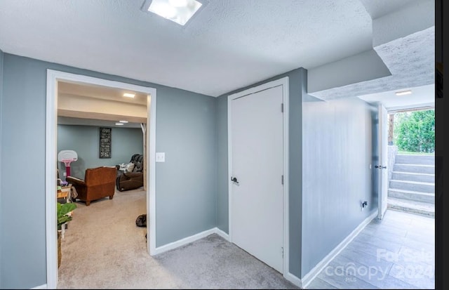 hall featuring light carpet and a textured ceiling