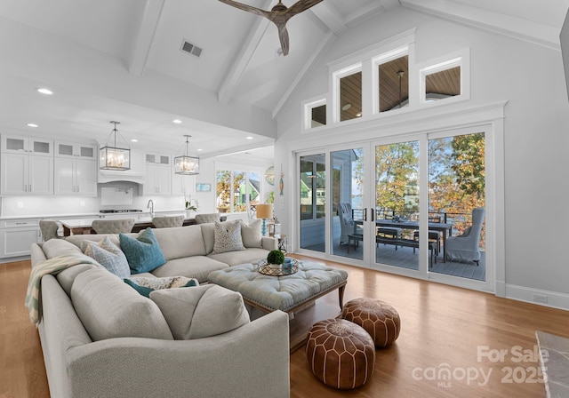 living room featuring light wood-type flooring, beamed ceiling, a healthy amount of sunlight, and high vaulted ceiling