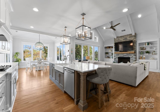 kitchen featuring sink, a center island with sink, white cabinetry, and hanging light fixtures