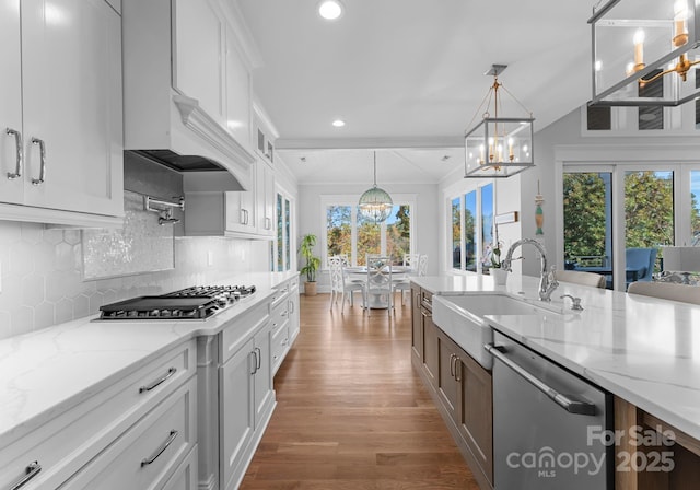 kitchen with light stone countertops, appliances with stainless steel finishes, hanging light fixtures, white cabinets, and sink