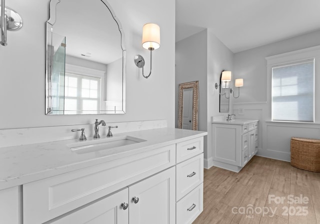 bathroom with wood-type flooring, vanity, and a healthy amount of sunlight