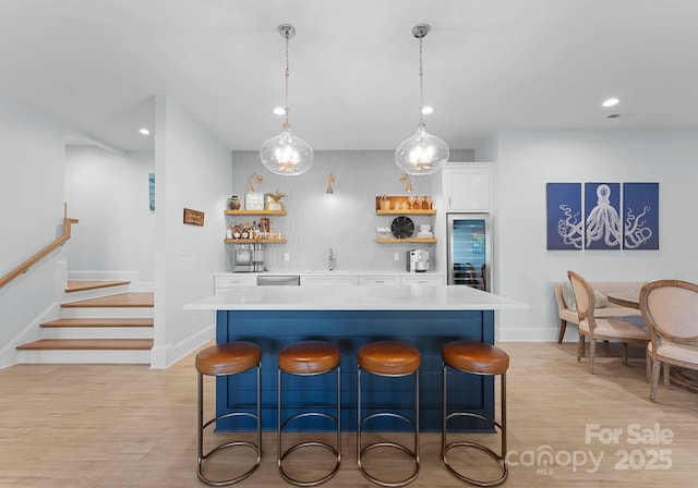 kitchen with a center island, a breakfast bar area, white cabinetry, and pendant lighting