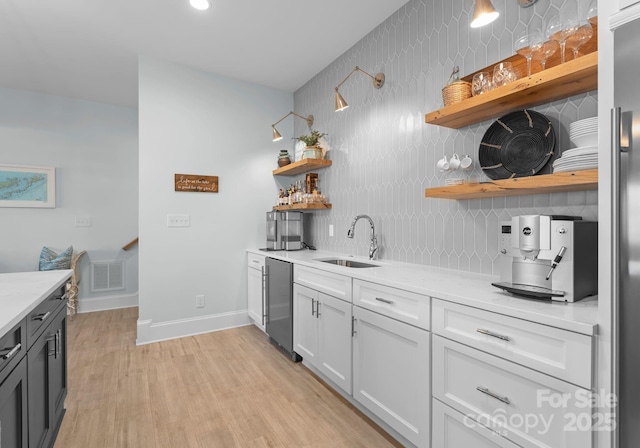 kitchen featuring sink, white cabinets, light wood-type flooring, light stone counters, and stainless steel appliances