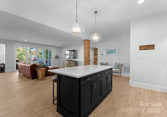 kitchen with a kitchen island, light hardwood / wood-style floors, a breakfast bar area, and hanging light fixtures