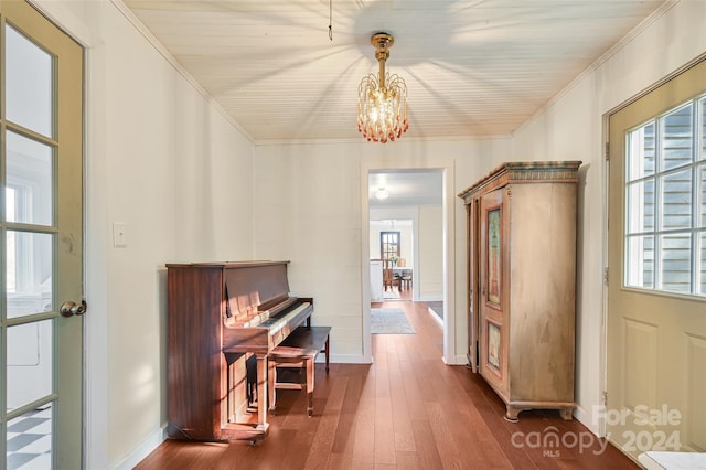 misc room with dark hardwood / wood-style floors, an inviting chandelier, a healthy amount of sunlight, and crown molding