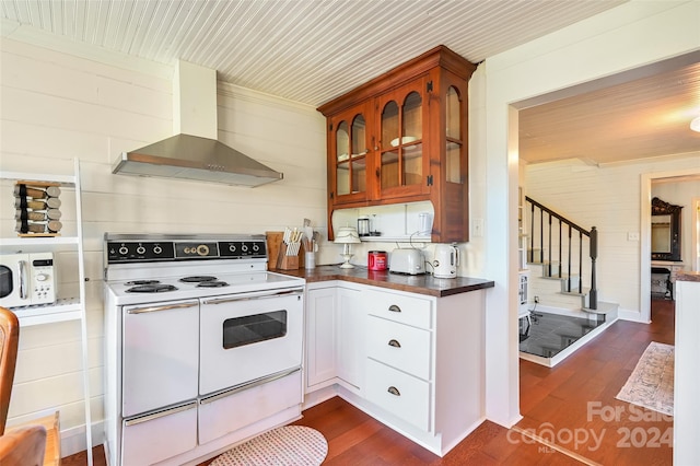 kitchen featuring wood walls, white appliances, wall chimney range hood, dark hardwood / wood-style flooring, and white cabinetry