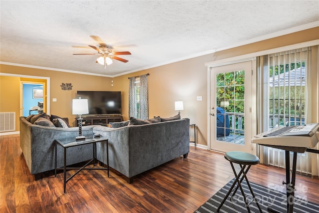 living room with ceiling fan, dark wood-type flooring, a textured ceiling, and ornamental molding