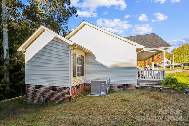 view of side of home with a porch, a yard, and cooling unit